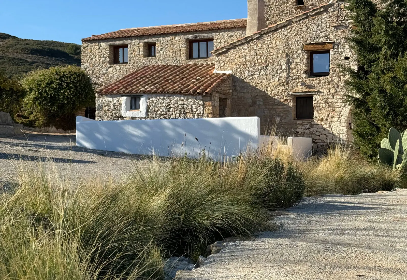 Fachada de piedra de Masía La Costereta y jardín a la luz del día
