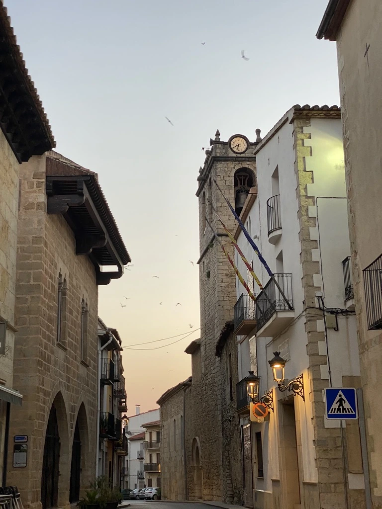 Calle del casco histórico de Catí, con fachadas de piedra y torre del reloj