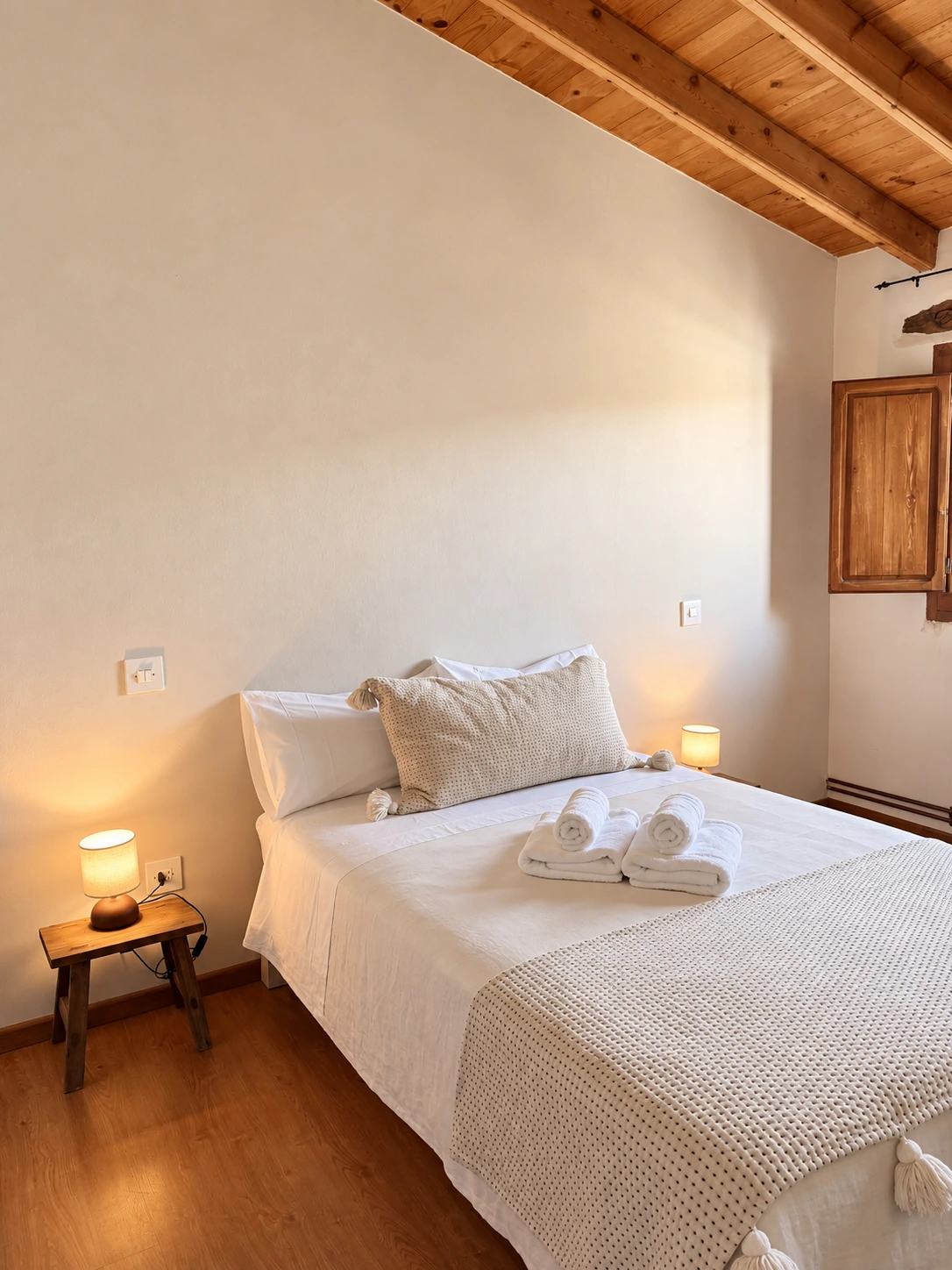 Cama de matrimonio con ropa de cama blanca y lámparas encendidas