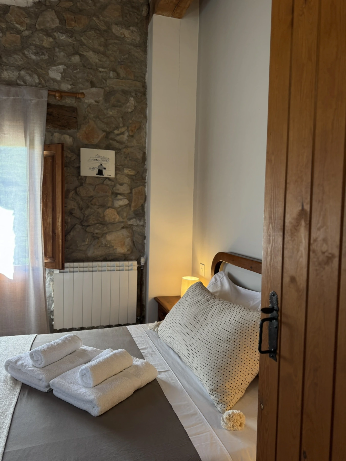 Dormitorio de matrimonio visto desde la puerta, con pared de piedra en Masía La Costereta
