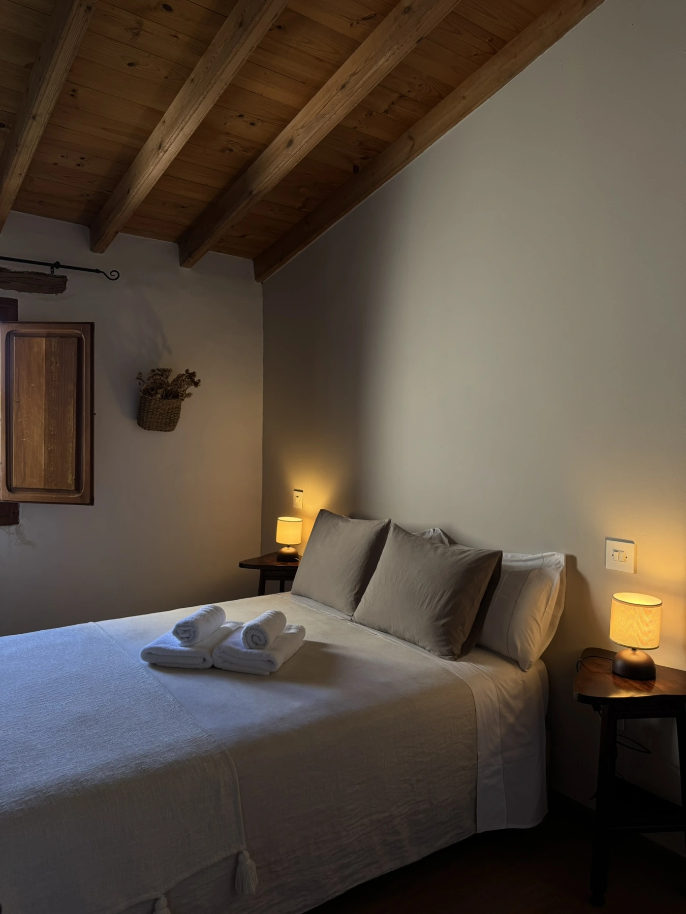 Dormitorio de matrimonio con cojines y luz cálida en Masía La Costereta
