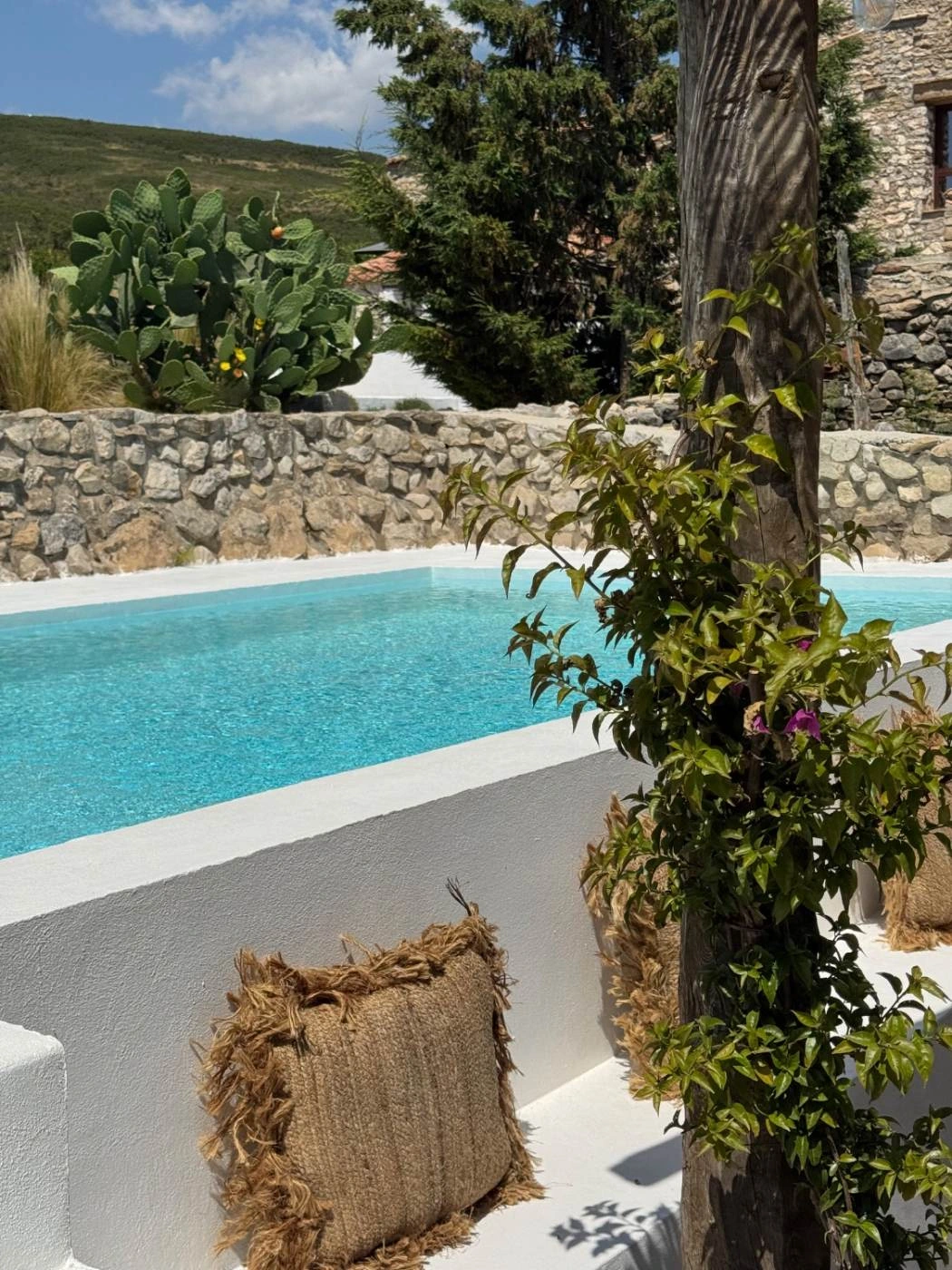 Piscina privada de la masía junto al banco con cojines y la pérgola